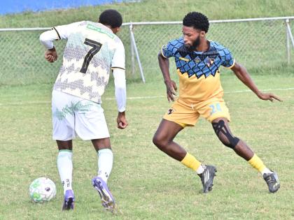 Racing United’s Andrew Campbell (right) tries to stop Treasure Beach’s Karim Bryan during a Jamaica Premier League football game at Ferdi Neita Park yesterday. Racing were 4-1 winners.