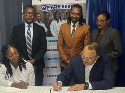 Minister of Health & Wellness, Dr Christopher Tufton and Tasheka Anderson, a parent who will benefit from the Family Caregivers' Pilot Programme sign the caregiver agreement form as the programme is officially launched at the Bustamante Hospital for 