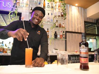 Mixologist Conroy Plummer happily prepares a tall glass of the pasi-flora.