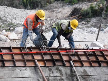 This 2020 photo shows workers pouring concrete in a retaining wall along the St Thomas main road