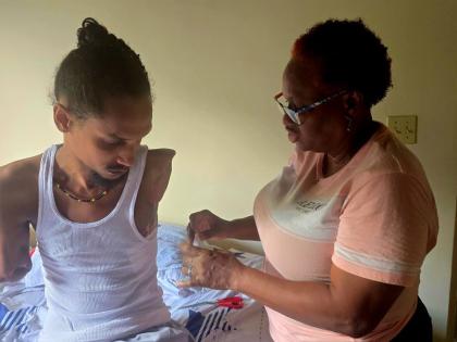 Bridgette Samuels Johnson dresses her son Chace Singh’s wounds at their home in Holland Estate, Trelawny.