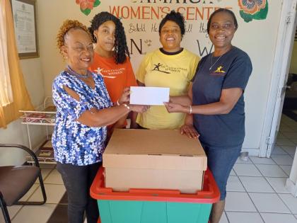 Vana Taylor (left), chairman of the JHTA Ocho Rios-Runaway Bay Chapter, presents a cheque and boxes of food items to Barbara Richards, director of Adult and Teen Challenge, as two members of staff look on.