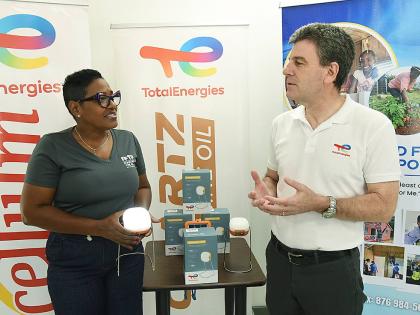 Marsha Burrell Rose (left), marketing and public relations manager, Food For The Poor, Jamaica, gets a feel of the Sunshine 150 Solar Lamp, 1,164 of which were donated by TotalEnergies Jamaica’s managing director, Vincent Daniault, assisting the charity 