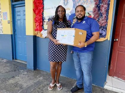Hakeem Atkinson (right), member relations supervisor at the Jamaica National Group, presents books to Thamar Russell-Brown, acting principal at the Allman Town Primary School. The donation was presented to the school following a book drive organised by the