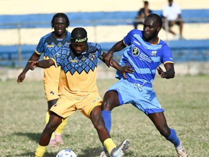 Racing United’s Nickyle Ellis (centre) shields the ball from Nickache Murray of Molynes United during their Jamaica Premier League encounter at the Constant Spring playfield yesterday.