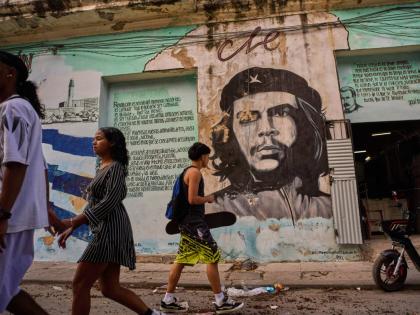 People walk past a mural of Che Guevara in Havana