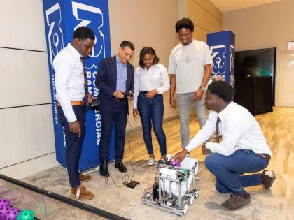 From left: Romario Lindo, captain of St Mary’s Technical High School; Andrew Pearman, director, NCB Foundation; and coaches Tashiba Julius and Gavin O’Meally test the team’s robot, ‘Small Fry’, under the guidance of Ackeem Gordon, sixth form stud