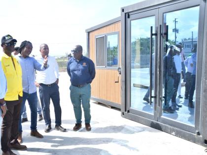 Minister of Local Government and Community Development, Desmond McKenzie (left), listens as Chief Engineering Officer at the Trelawny Municipal Corporation, Kayon Hall (second left), provides details on one of the units at the Trelawny Infirmary’s new lo
