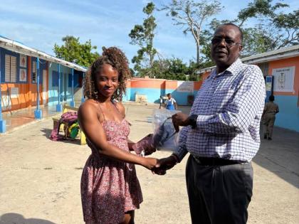 Gerald Miller (right), health promotion and education officer for Westmoreland, hands over a Drop Filter to a parent at Broughton Primary School after demonstrating how to use the device to access safe drinking water.
