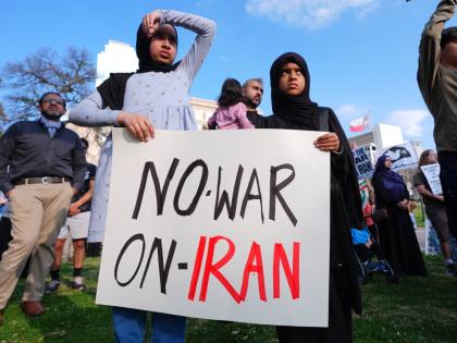 Children hold a sign protesting war against Iran during an antiwar demonstration at Dealey Plaza in downtown Dallas.
