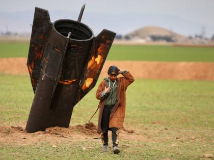 A shepherd boy walks away from an unexploded Iranian projectile that landed in an open field in the outskirts of Qamishli, eastern Syria.