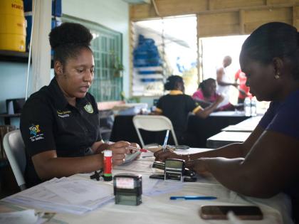 A representative from the Tax Administration Jamaica (TAJ) assists a resident of Savanna-la-Mar with documentation at the Project STAR Civil Documentation Community Hub, hosted at the New Market Oval Community Centre.