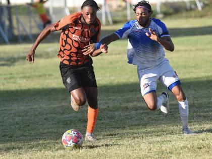 Joshua Dewar (left) of Tivoli Gardens FC dribbles away from Dunbeholden FC’s Odane Samuelsduring their  Jamaica Premier League match at the Edward Seaga Sports Complex yesterday.