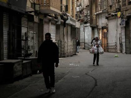 A woman carries her groceries as people walk along the mostly empty Tehran traditional main bazaar, where most shops are closed, in Tehran, Iran on March 10, 2026. (AP Photo/Vahid Salemi)