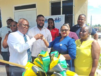 Mayor of Montego Bay Richard Vernon (centre) looks on as Senator Charles Sinclair, councillor for the Montego Bay North West Division in the St James Municipal Corporation, presents the key to the renovated Flankers Postal Agency to Mytha Bahadur, regional