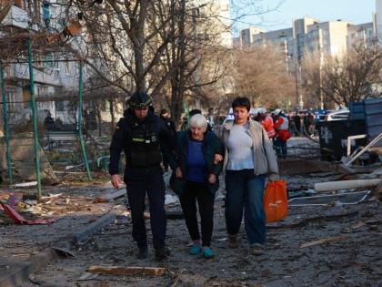 A rescuer helps an elderly woman to leave her home damaged by Russian aerial guided bomb in Zaporizhzhia, Ukraine.