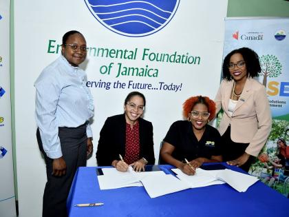 EFJ boss, Nicole Adamson (seated left) and JPS Foundation Head, Sophia Lewis (seated right) sign the MOU while Joni Jackson (left), project manager for the J-USE project, and Audrey Williams, media and public relations manager at JPS, witness the signing.