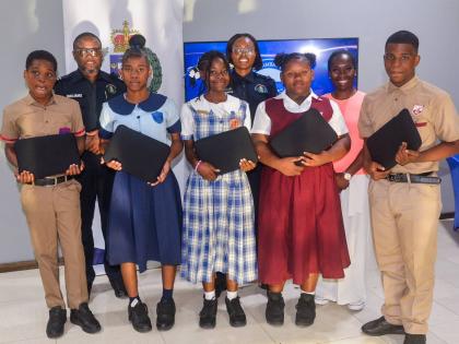 Left: Sheldon Walters, Britany Thompson, Elizabeth Cunningham, Ashley Jones, and Justine Stone, students who recently received laptops. In the background (from left): Territorial Officer for the St Catherine North Police Division, Inspector Ishmael William