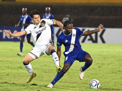 L.A. Galaxy’s Isaiah Parente (left) challenges Mount Pleasant’s Warner Brown during last night’s Concacaf Champions Cup at the National Stadium. LA Galaxy won 3-0.
