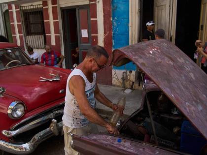 A man finishes putting fuel in his car's tank, located in the back of the car, during a blackout in Havana, Cuba, Monday, March 16, 2026. (AP Photo/Ramon Espinosa)
