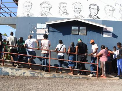 This file photo shows people waiting to exercise their franchise on election day.