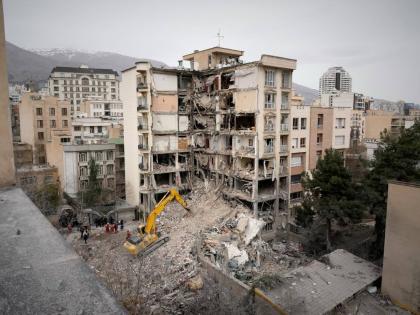 Iranian Red Crescent emergency workers use a bulldozer to clear rubble from a residential building that was hit in US-Israeli strike in Tehran, Iran