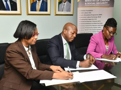 Minister of Labour and Social Security, Pearnel Charles Jr., is joined by Acting Permanent Secretary, Dione Jennings (left), and President of the Jamaica Household Workers Union (JHWU), Elaine Duncan, in signing a Memorandum of Understanding (MOU) at the M