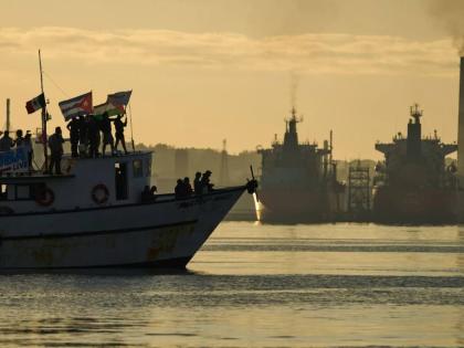 Activists wave Cuban and Palestinian flags from the vessel Maguro, arriving from Mexico with humanitarian aid as part of the "Nuestra America," or Our America convoy, in Havana Bay, Cuba, Tuesday, March 24, 2026. 