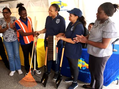 President of the Majesty Gardens Community Development Corporation, Jaheim Mitchell (second left), receives cleaning tools from Pan American Development Foundation Project Coordinator, Kimberly Seymour-Brown, at the Community Clean-up, E-Waste Drive, and t