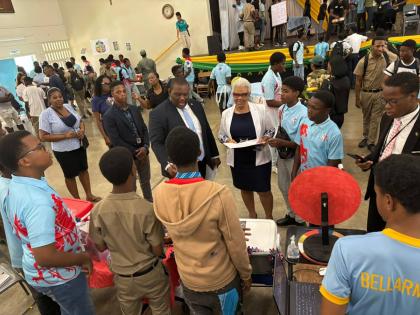 Senator Marlon Morgan, parliamentary secretary in the Ministry of Education, Skills, Youth and Information, engages with a group of students at the STGC Teen Biz Expo 2026 as St George’s College Principal Margaret Campbell looks on.