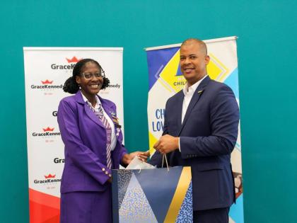 GraceKennedy Group CEO Frank James presents a laptop to Aldi-Anna Lewis, sixth form student at deCarteret College, and the 2025 Top Performer in the National Child Month Committee’s (NCMC) Youth Academic Achievement Awards. The presentation took place du