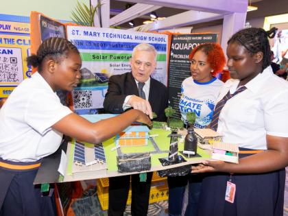 Damian Obiglio (second left), chairman of the JPS Foundation, and Sophia Lewis (second right), head of the JPS Foundation, engage with Abigail Dixon (left) and Ajada Duffus of St Mary Technical High School as they present their solar-powered hydroponics an