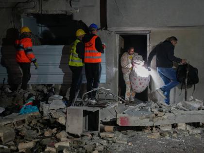 Residents carry personal belongings as they leave a building damaged in a missile strike in Tel Aviv, Israel on March 28, 2026. (AP Photo/Maya Levin)