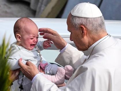 Pope Leo XIV caresses a child after presiding over Mass in St Peter’s Square at the Vatican on the Catholic feast of Palm Sunday.