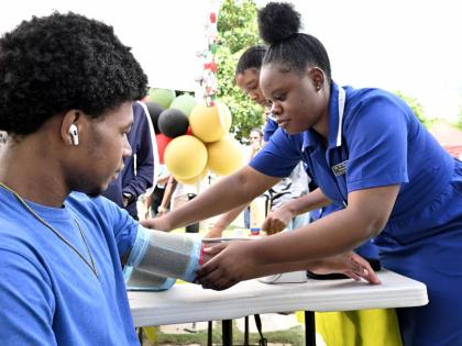 Nursing students Ashanti Mootie (right) check Tajay Fuller’s blood pressure during the College of Health Sciences’ annual health fair, held yesterday at UTech’s campus in St Andrew. 
