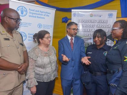 Indian High Commissioner to Jamaica, His Excellency Mayank Joshi (centre), makes a point to Head of the Guanaboa Vale Police, Sergeant Navelette Davis-Leachman (right), and Constable Leonie Angus (second right), during the recent certification ceremony for