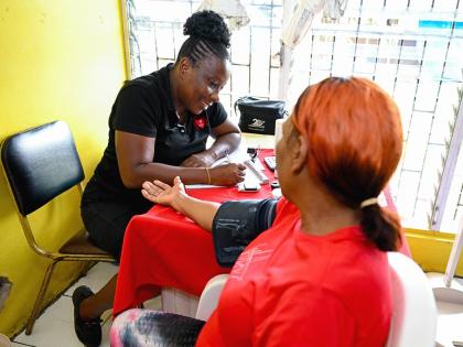 Medical assistant at the Heart Foundation of Jamaica (HFJ),  Donna-Marie Dacres, records a patient’s blood pressure results during the St Catherine High School’s health fair held at the institution recently. 