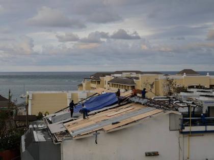 In this October 31, 2025, photo people are seen repairing the roof of a resort in Montego Bay, Jamaica, in the aftermath of Hurricane Melissa.