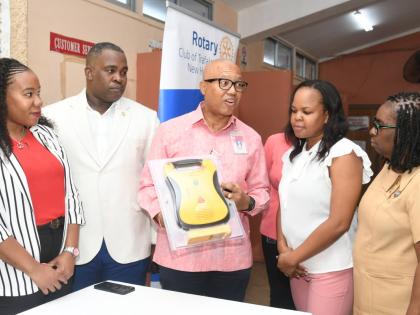 Professor William ‘Bill’ Aiken (centre), district governor for Rotary District 7020, explains how the defibrillator should be used to Dr Wendy-Ann Byfield-Lyons (second from right), medical officer in charge of the Duhaney Park Health Centre in St Andr
