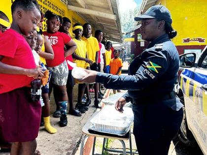 Corporal Chevon McKoy serves bun and cheese to students at Jubilee Primary School on Wednesday. 