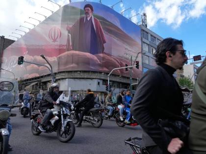 People drive their motorbikes past a billboard that shows a graphic depicting Iran's Supreme Leader Ayatollah Mojtaba Khamenei in downtown Tehran, Iran in April 6, 2026. (AP Photo/Vahid Salemi)