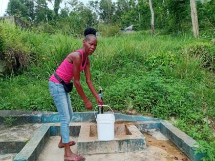 A resident of Beecher Town, St Ann, collects water from a community standpipe.
