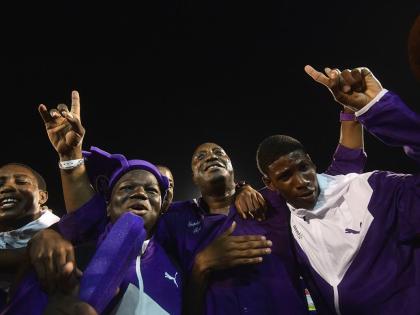 Kingston College principal Dave Myrie (centre) celebrates with athletes after winning the 2019 Boys’ title at Champs.