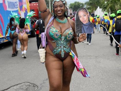 Kia-Simone Bell of Yard Mas parades along East Kings House Road on Sunday, carrying a photo poster of her absent friend while celebrating Carnival in Jamaica’s road march.