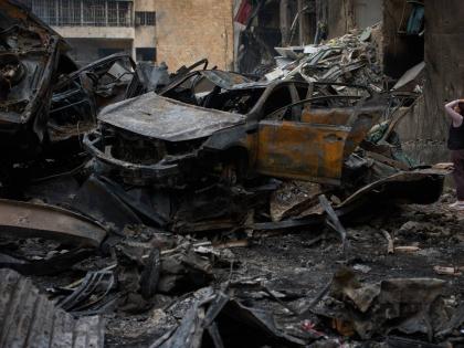 A resident checks damage to buildings as she walks near charred cars, at the site of Wednesday’s Israeli airstrike, in Beirut, Lebanon, on Friday.