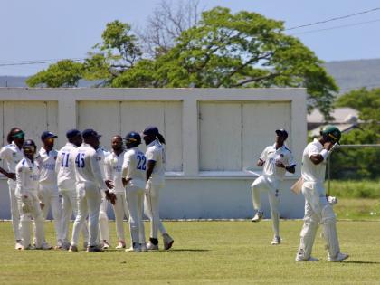 A dejected Romaine Morris (right) leaves the field after being dismissed by Jomel Warrican as the Barbados Pride celebrate on day three of their West Indies Championship game at Chedwin Park yesterday.