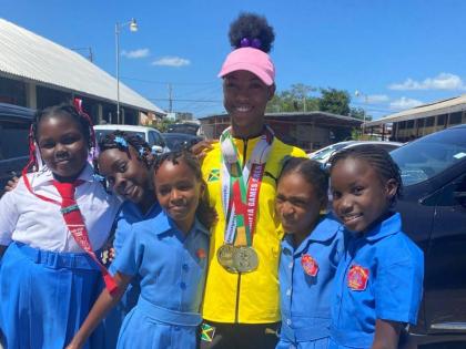 Foga Road High’s Shameika McLean (pink cap) with students from her former school, May Pen Primary, during a parade through the streets of the parish capital yesterday to celebrate the achievements of  Foga Road’s athletes at the ISSA/GraceKennedy Boys 