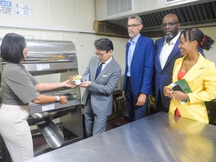 Founder of Mel’s Sticky Jams Limited, Melissa Tavares-Wilson (left), presents Ambassador of Japan to Jamaica, Kohei Maruyama, with one of her pineapple and ginger flavoured jams during a tour of the agro-processing area located at the Jamaica Business De