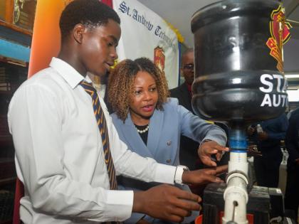 Minister of Education, Skills, Youth and Information, Senator Dr Dana Morris Dixon (second left), examines an automatic chicken feeder made by students of St Andrew Technical High School, during an alumni engagement visit on April 14, in commemoration of t
