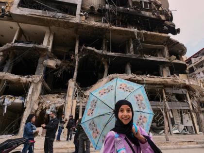 A girl passes in front of a destroyed building, following a ceasefire between Hezbollah and Israel in Dahiyeh, Beirut’s southern suburbs, Lebanon.
